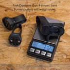Black electronic device on a digital scale with text about Trek Domane Gen 4 on a wooden surface.